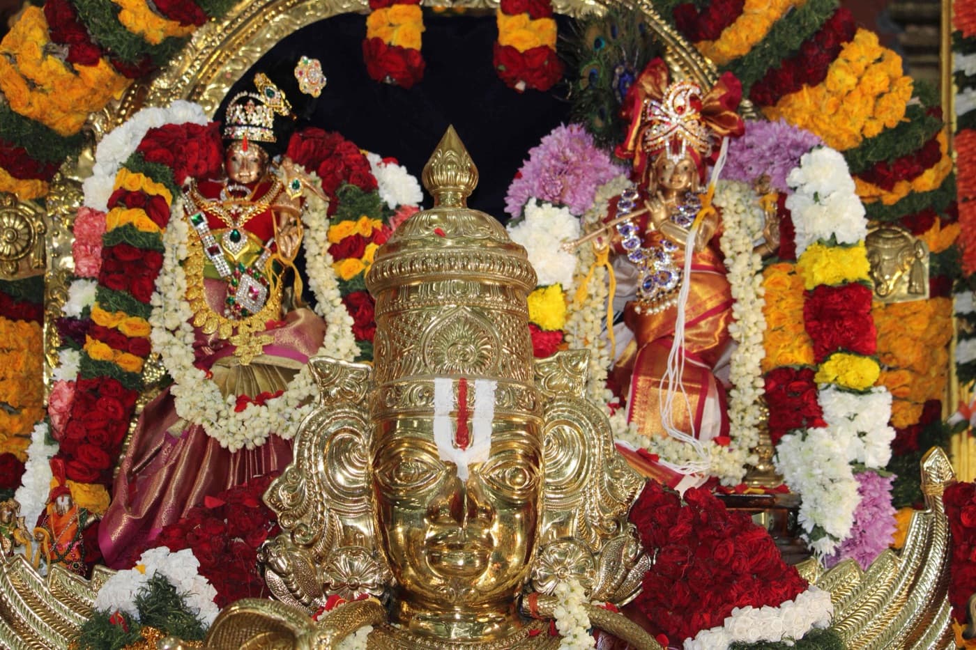 Garlanded golden processional deities adorned for a festival
